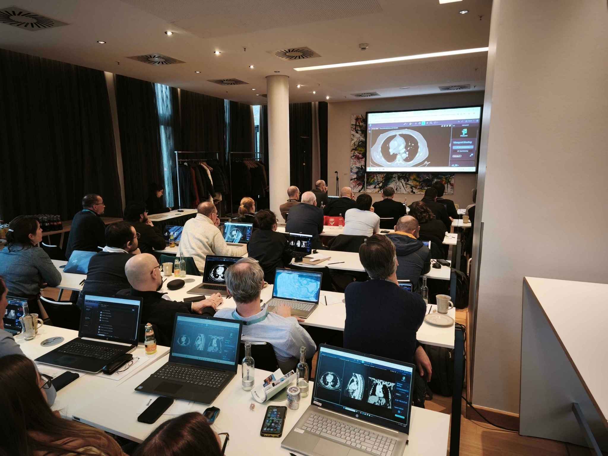 Session de formation interactive en congrès de radiologie : participants analysant des cas cliniques sur ordinateur avec un formateur.